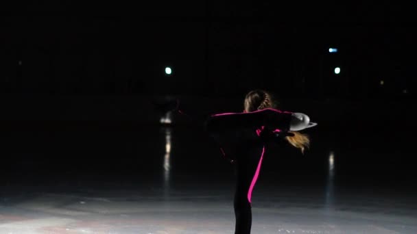 Petite fille patineuse effectue une rotation debout dans l'arène du stade de glace. Tient un patin d'une main — Video