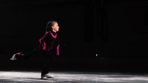Професійний ковзаняр робить стрибок на ковзанах з обертанням в повітрі на льоду. Маленька дівчинка-портрет на змаганнях з фігурного катання . — стокове відео