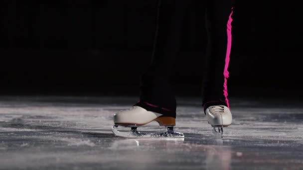 Primo piano, le gambe nei pattini da ghiaccio vanno sul ghiaccio e si muovono nella cornice. La telecamera si muove dinamicamente dietro i pattini. Pattinaggio artistico professionale — Video Stock