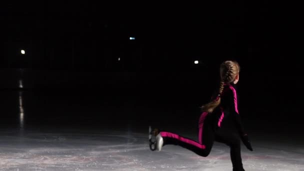 Een professionele skater voert een schaatsen sprong met de rotatie in de lucht op het ijs. — Stockvideo