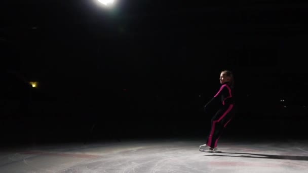 Professionele meisje schaatser bewegingen op het ijs op de schaats met benen ontvouwd aan de zijkanten. De camera beweegt mee. Vertraagd schieten professioneel schaatsen. — Stockvideo