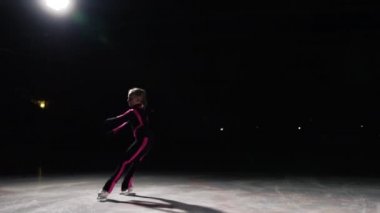 Bir profesyonel kız patenci ayakları taraf için dağıtılır ve kamera ile birlikte hareket ediyor buz üzerinde paten pozisyonda bir daire içinde taşır. Profesyonel buz pateni çekim gecikmiş. Arka ışık