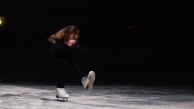 Siyah bir takım elbise içinde profesyonel artistik patinajcı buz buz pateni ağır çekim shot üstleri gücünü gerçekleştirir.