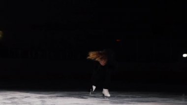 Küçük kız skater bir iplik ayakta buz Stadyumu arenada gerçekleştirir. Bir paten tek elle tutan.