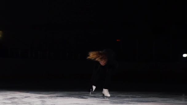 Kleine Eiskunstläuferin dreht sich stehend in der Arena des Eisstadions. hält einen Schlittschuh mit einer Hand. — Stockvideo