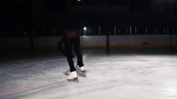 Close-up of a girl skater on ice carries out a rotation around her axis while standing on ice skates on one leg. Camera moves in orbit around the figure skater in slow motion — Stock Video