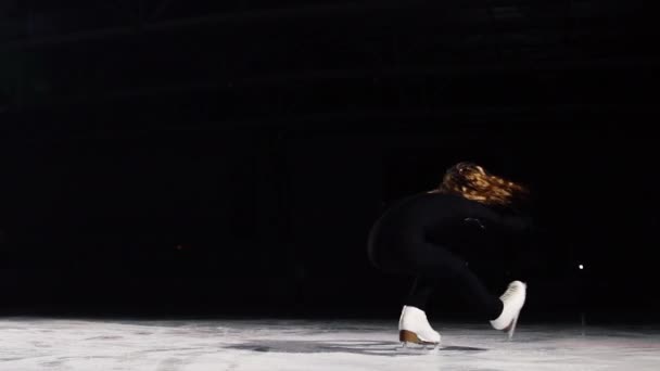 Een professioneel kunstschaatser voert schaatsen met een bocht te draaien een top spinnen met haar as op een zwarte achtergrond. — Stockvideo