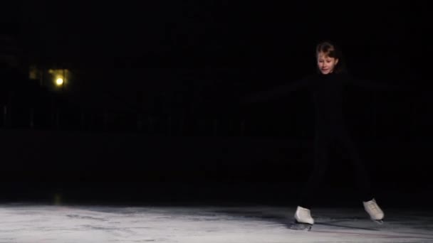 Una mujer profesional, patinadora de un traje negro en una competición de patinaje artístico, entra en el marco abruptamente se queda en su lugar y mira a la cámara . — Vídeo de stock