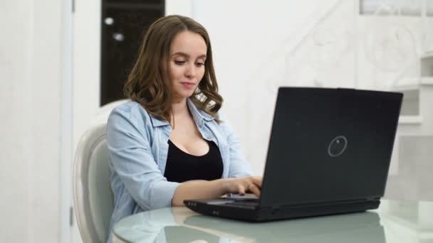 Una mujer embarazada se dedica a los negocios durante el permiso de maternidad. Sentada en la computadora acariciando su vientre y hablando con el bebé en el vientre. Imprime un mensaje en el teclado de su computadora portátil. Se comunica con — Vídeo de stock