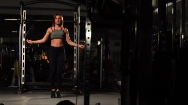 Spor, etkinlik. İp atlama ile sevimli bir kadın. Kaslı kadın siyah arka plan.