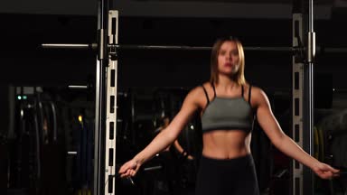 Spor, etkinlik. İp atlama ile sevimli bir kadın. Kaslı kadın siyah arka plan.