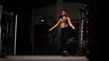 Spor, etkinlik. İp atlama ile sevimli bir kadın. Kaslı kadın siyah arka plan.