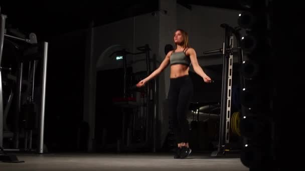 Spor, etkinlik. İp atlama ile sevimli bir kadın. Kaslı kadın siyah arka plan. — Stok video