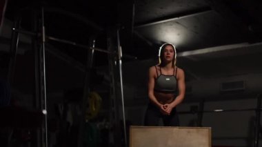 Gizli yüz ile en iyi ve kısa tayt giyen siyah spor karanlık bir spor salonunda kutusunu atlar güzel kadın fitness atlet gerçekleştirir