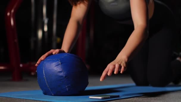 Een brunette atletische bouwt push-ups op een mache in de sportschool een stopwatch te zetten van de mobiele telefoon. Boksen opleiding, vechtsport. — Stockvideo