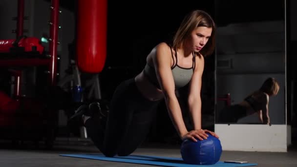 Een brunette atletische bouwt push-ups op een mache in de sportschool een stopwatch te zetten van de mobiele telefoon. Boksen opleiding, vechtsport. — Stockvideo