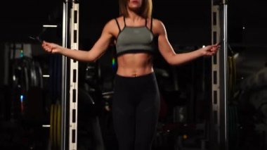 Spor, etkinlik. İp atlama ile sevimli bir kadın. Kaslı kadın siyah arka plan.