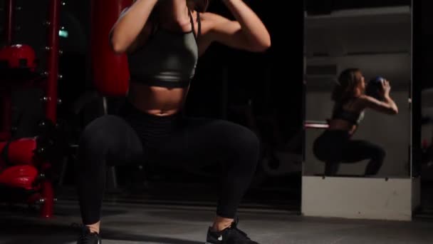 Jeune femme athlétique accroupi avec un ballon de médecine au mur — Video