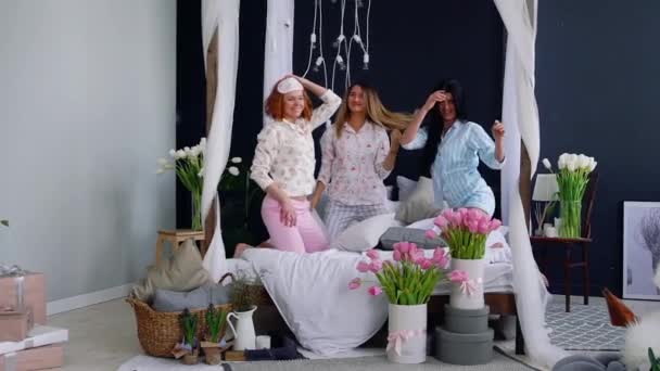 Trois jeunes femmes sexy se battant contre des oreillers lors d'une soirée pyjama en l'honneur du mariage. Belle femme riant et souriant ludique. Une soirée pyjama. Danse sur le lit avec ses amis . — Video