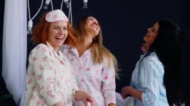 Bayan pijama partisi, üç güzel ve seksi kız gülmek ve yatağa dans.