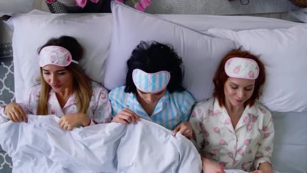 トップ ビュー 3 つの美しい女の子が行き、ベッドの上で寝る、寝る目包帯を置く. — ストック動画