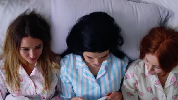 Vista superior, tres hermosas novias chicas se van a la cama en pijama lindo en una cama acogedora recordando la infancia. Hermanas amorosas . — Vídeos de Stock