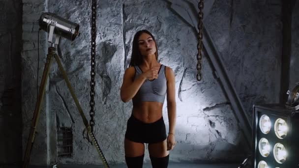 Slank oppblåst vakker kvinnelig idrettsutøver på bakgrunn av steinmurer varmer opp halsen din før trening – stockvideo