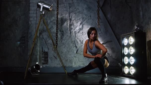 Sport sexy dívka v krátké šortky prohřívá svaly nohou a hýždí před zahájením tréninku. — Stock video