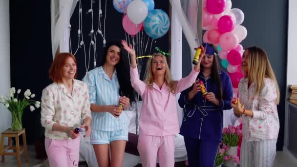 Um grupo de garotas rindo e sorrindo de pijama lançando confetes em câmera lenta 120 quadros por segundo. Jogue airbags doces brilhantes em uma festa — Vídeo de Stock