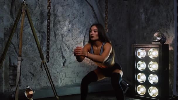 Atleta atleta sexy menina executa agachamentos em shorts curtos no estúdio. Exercícios para músculos da coxa. Belas ancas. Personal trainer mostra técnica de exercício . — Vídeo de Stock