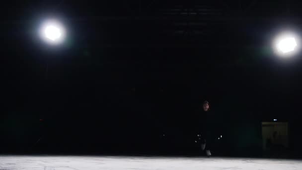 美しい輪郭光と黒のスーツのスケーターでは加速し、突然停止します。スケートから氷の破片を飛んでください。 — ストック動画
