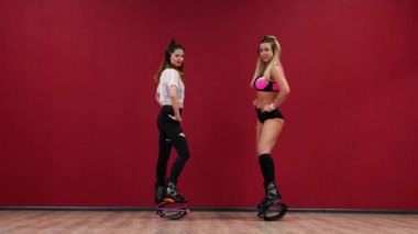 Güzel seksi kız fitness egzersizleri özel ayakkabıları kango atlama yapıyor bir kırmızı arka plan duvar