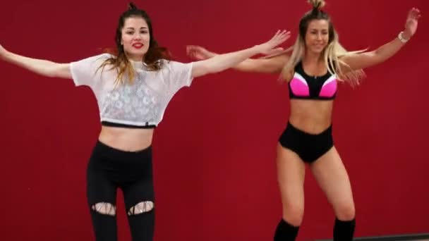 Mooi sexy meisje op een rode achtergrond muur doen van fitness oefeningen op een speciale schoenen kango sprong — Stockvideo