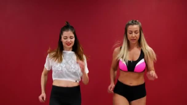 Mooi sexy meisje op de achtergrond van een rood muur Voer lopende oefeningen in de sportschool in speciale lente jassen. Vrolijke opleiding met kango springen — Stockvideo