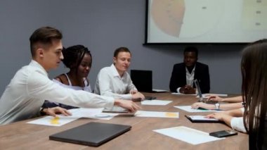 Yaratıcı çok etnik gruptan yöneticileri bir grup sökmeye konferans salonunda Yönetim Kurulu toplantısında şirket geçen yıl için kar grafikler. Afrikalı-Amerikalı bir kız ve bir