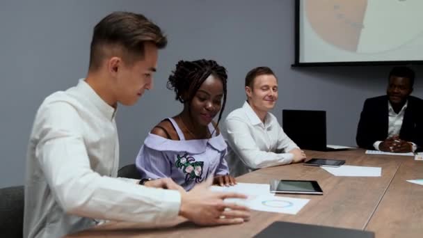 En grupp kreativa multietniska chefer isär vid mötet i styrelsen i konferenssalen grafer av förra årets i företaget. En afrikansk-amerikansk flicka och en — Stockvideo