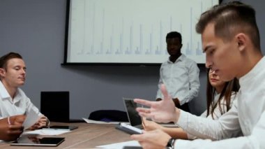 Afrika kökenli Amerikalı antrenör ofiste iş adamları için kurumsal tanıtım sağlar, koyu tenli işadamı yeni iş planı üzerinde beyaz tahta, istemcilere toplantısında hoparlör dinleme konuşma sunar