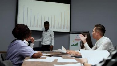 Afrika kökenli Amerikalı antrenör ofiste iş adamları için kurumsal tanıtım sağlar, koyu tenli işadamı yeni iş planı üzerinde beyaz tahta, istemcilere toplantısında hoparlör dinleme konuşma sunar