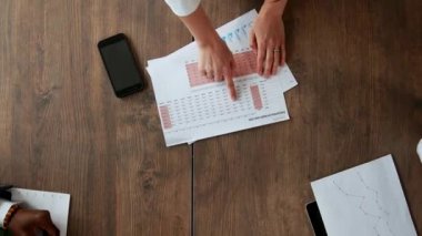 Üstten Görünüm büyük masanın arkasında beyin fırtınası farklı milletlerden yaratıcı yöneticilerin office ekibi yapar. Yakın çekim kamera hamle tablo boyunca yayılan finansal belgeler