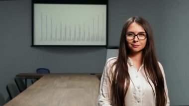 Kameraya bakarak gözlük ile toplantı odasında ayakta office elbiseleri güzel kız portresi