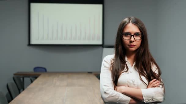 Портрет красивой девушки в офисной одежде, стоящей в конференц-зале с очками, смотрящей в камеру — стоковое видео