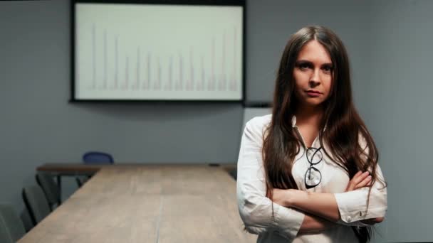 Портрет красивой девушки в офисной одежде, стоящей в конференц-зале с очками, смотрящей в камеру — стоковое видео