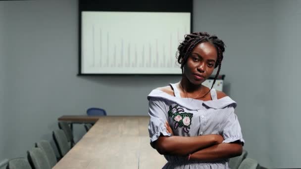 Porträtt av afrikanska amerikansk affärsman kvinna stående på kontor framför en stor tabell och grafer på skärmen tittar på kameran — Stockvideo