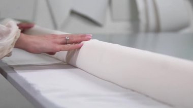 Giysi Tasarımcısı studio tablo üzerinde ölçümler ile çalışıyor. 4 k Uhd vurdu. Tatlı beyaz ve açık renkli dikiş yavaş beyaz kumaş skein dağıtın. el yapımı terzilik