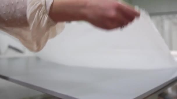 Concepteur de vêtements travaille avec des mesures sur une table de studio. Tourné en 4K UHD. Gros plan déployer une écheveau de tissu blanc en blanc et de couleur claire couture au ralenti . — Video