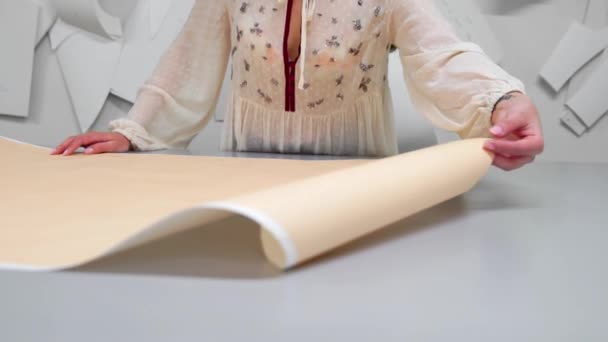 Young female designer with tape-line on her neck standing in dressmaking studio and drawing lines with chalk and rule. Female couturier in atelier cutting out a pattern for future clothes. — Stock Video