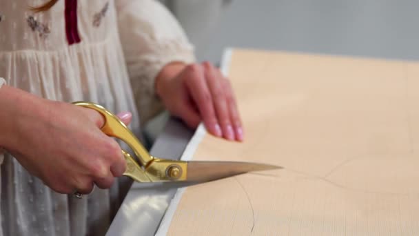 Jonge vrouwelijke ontwerper met tape-lijn aan haar nek permanent in de kleermakerij studio en lijnen met krijt en regel tekenen. Vrouwelijke couturier in atelier uitsnijden van een patroon voor toekomstige kleding. — Stockvideo