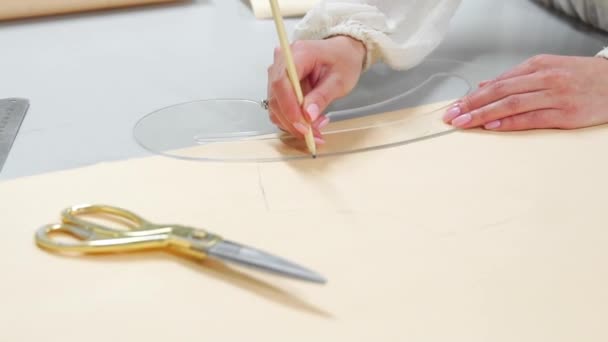 Jeune créatrice avec du ruban adhésif sur le cou debout dans un atelier de couture et dessinant des lignes avec de la craie et de la règle. Couturier femelle en atelier découpant un motif pour les vêtements futurs . — Video