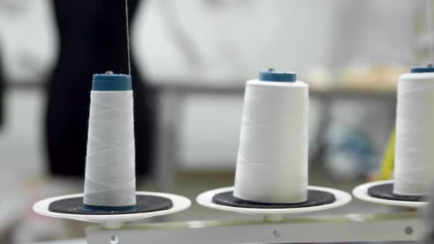 Closeup of three big bobbins with thin white thread on working professional sewing machine. Real time full hd video footage — Stock Video