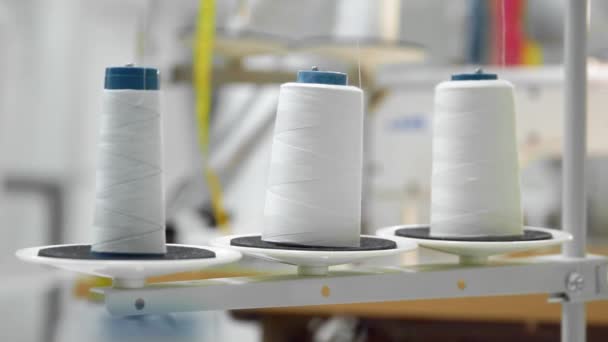 Primo piano di tre grandi bobine con filo bianco sottile sulla macchina da cucire professionale. In tempo reale full hd video — Video Stock